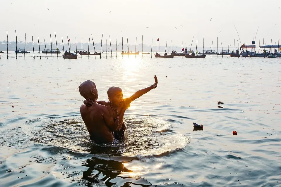 A pilgrim bathing at the Kumbh Mela at sunrise