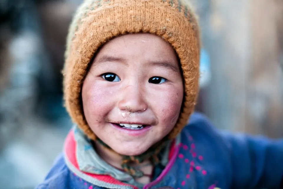 A smiling child in a knitted cap in Ladakh